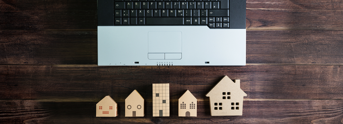 Wooden model houses by a laptop computer