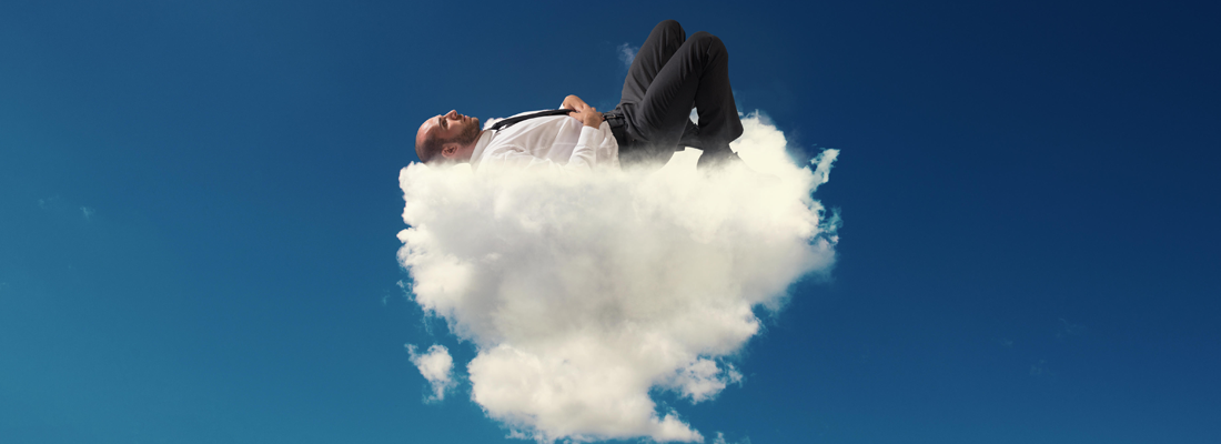 A man in a business suit asleep on a fluffy cloud